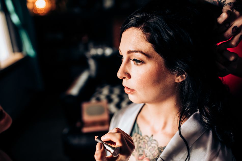 Side profile portrait in dramatic lighting showcasing elegant makeup and jewelry.