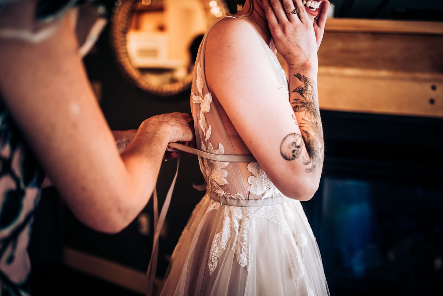 Close-up shot of a bride's tattooed arm in a delicate lace wedding dress.