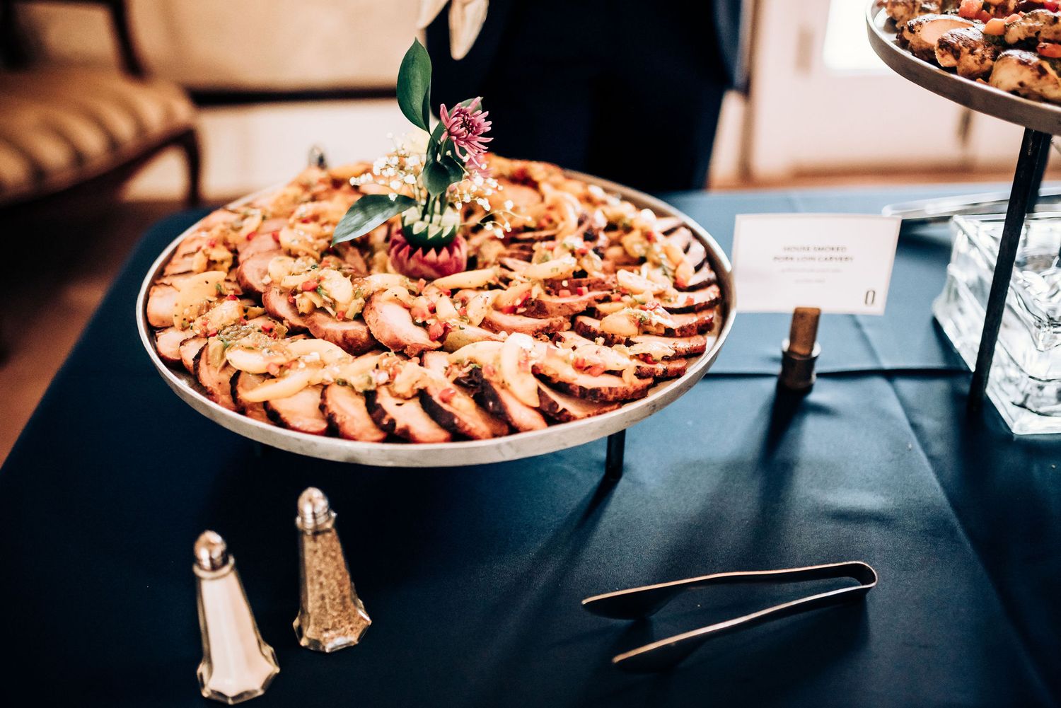An elegantly presented platter of sliced meats on a dark tablecloth with decorative salt shakers.
