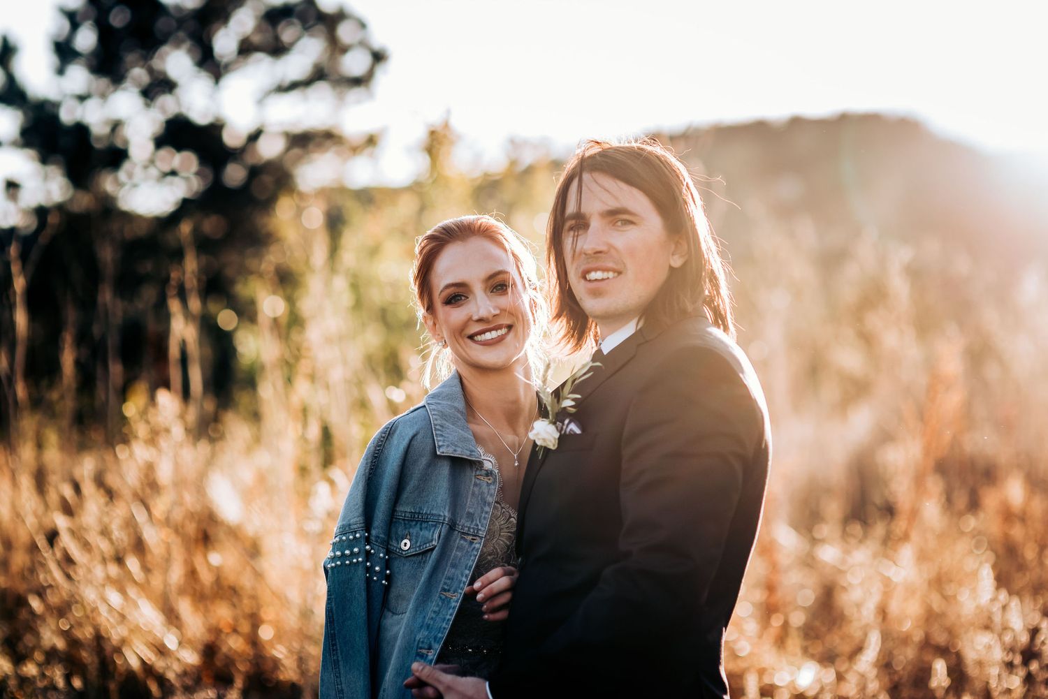 Casual wedding couple portrait in golden sunset light with denim jacket accent.