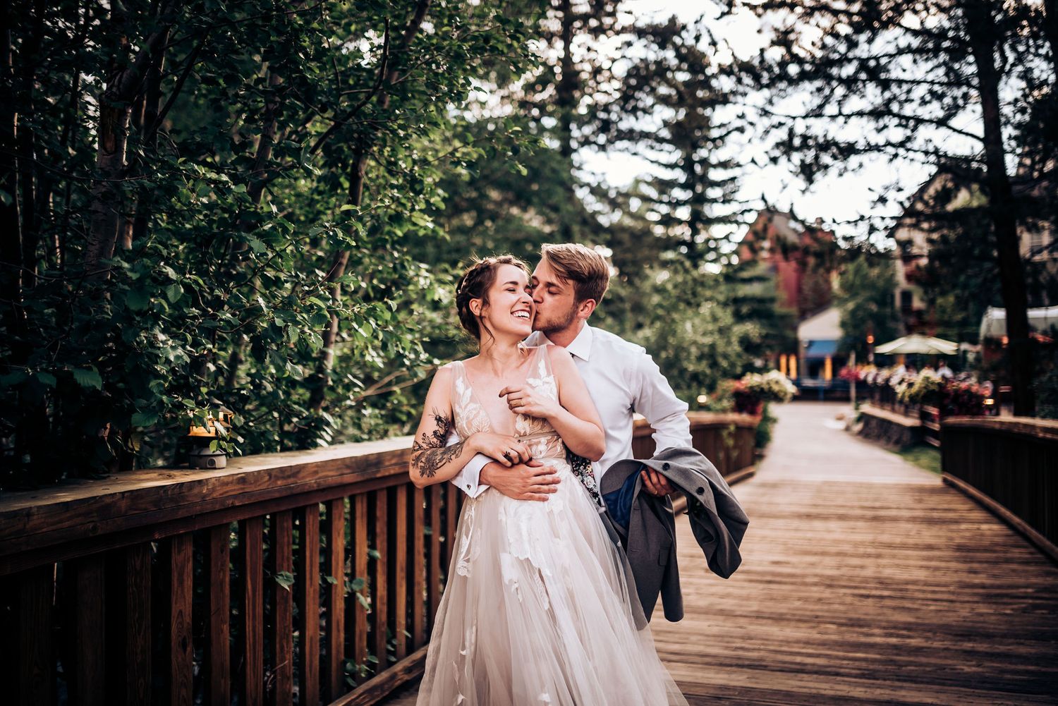 A romantic moment between newlyweds on a wooden bridge surrounded by forest scenery.