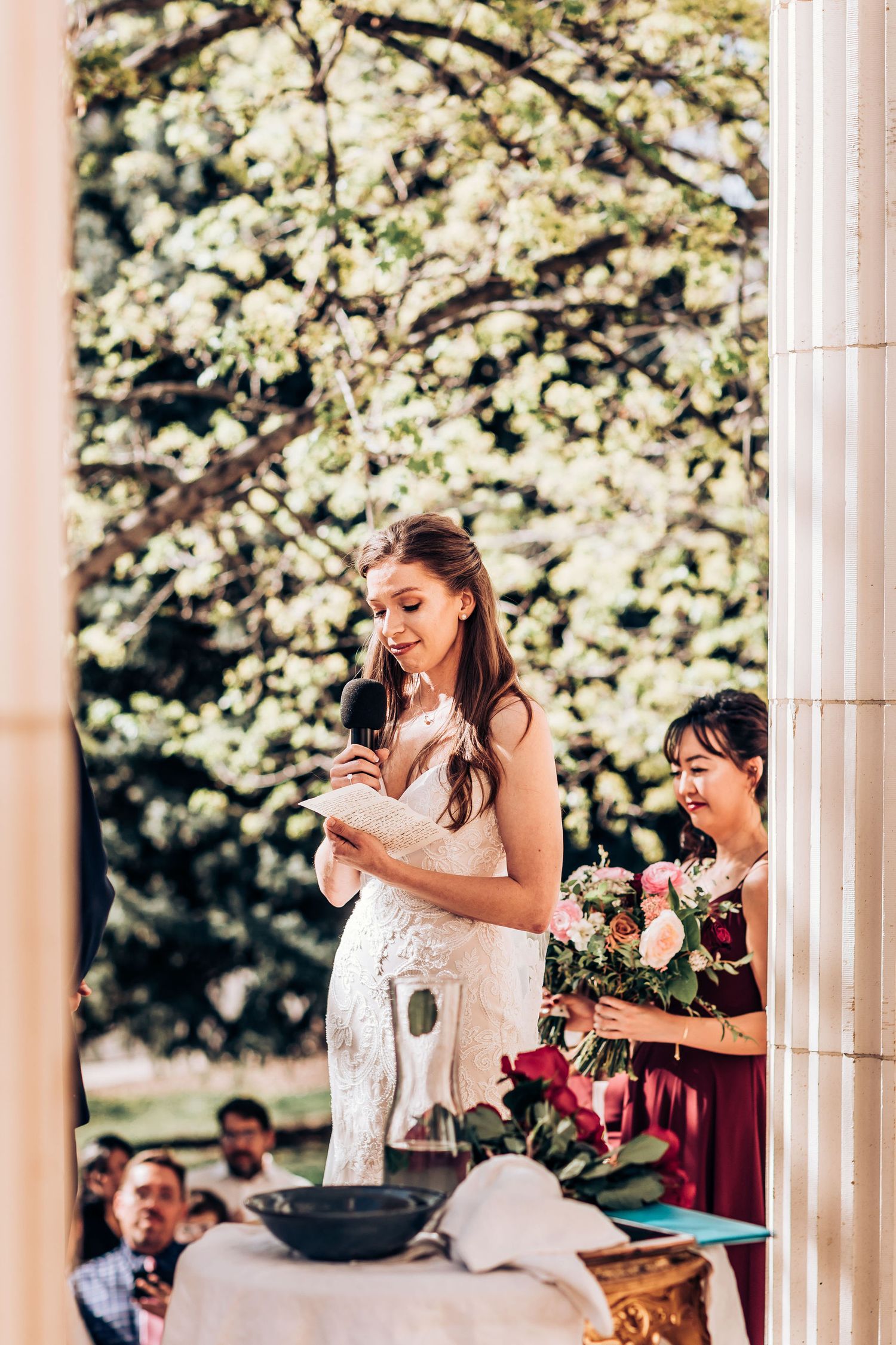 Spring wedding ceremony with blooming cherry blossoms and classical architecture in background.