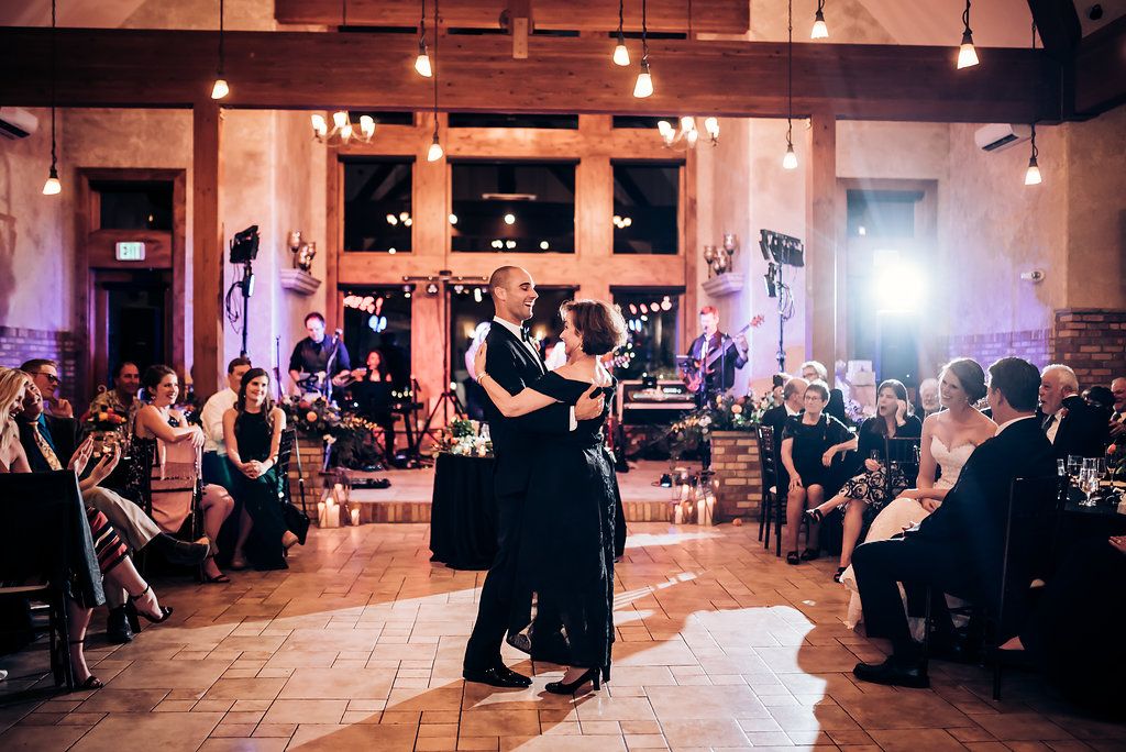 Wedding reception dance floor scene with guests watching couple's first dance in elegant venue.