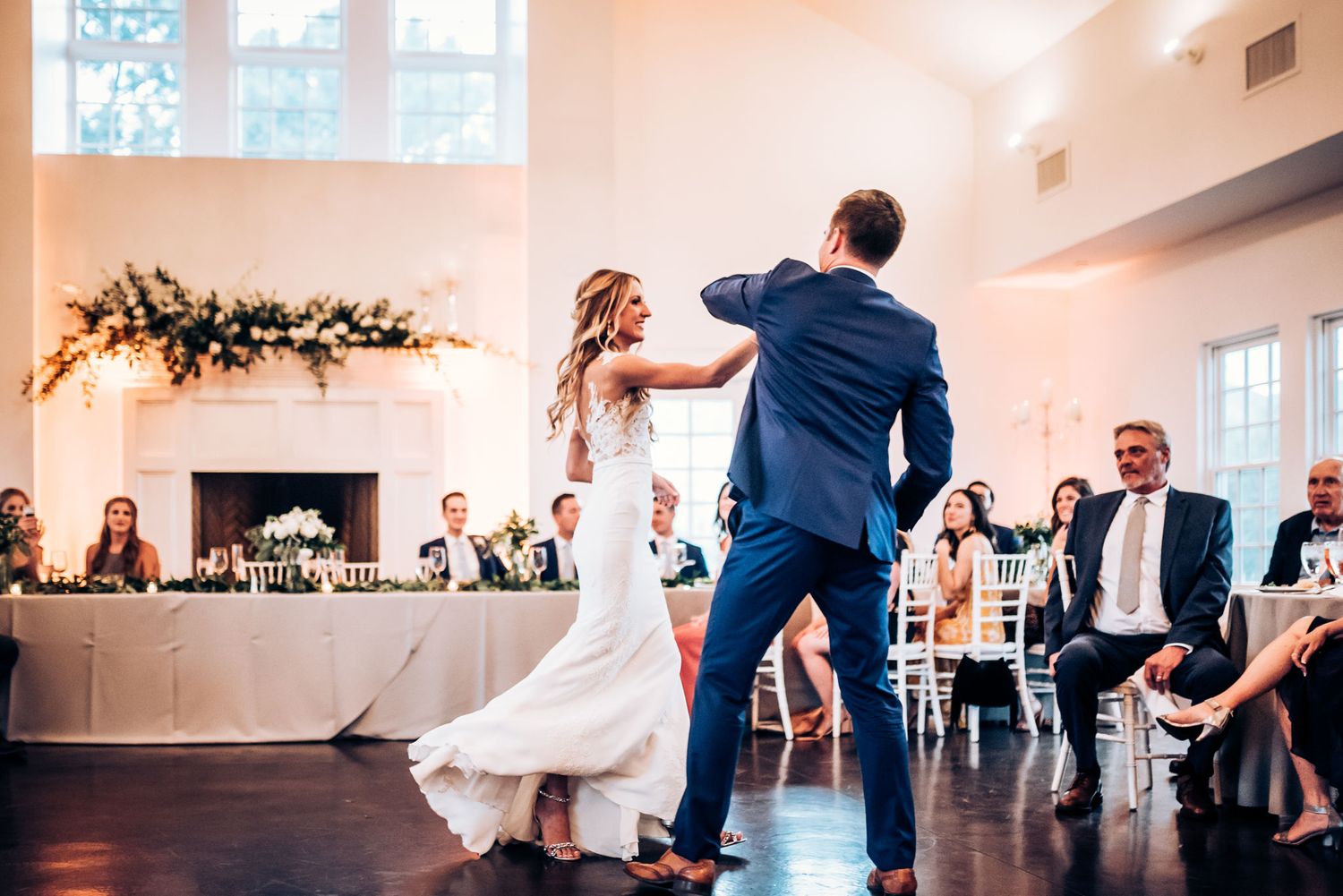 A couple performs their first dance at a wedding reception surrounded by guests.