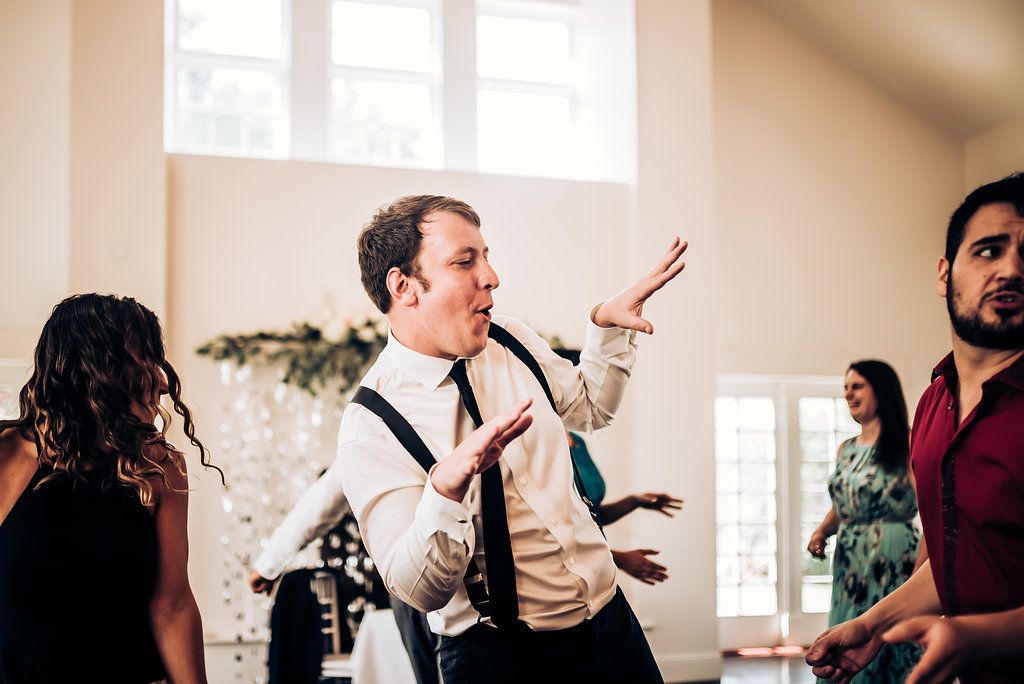 Guest singing passionately at a wedding reception with decorative floral arch in background.