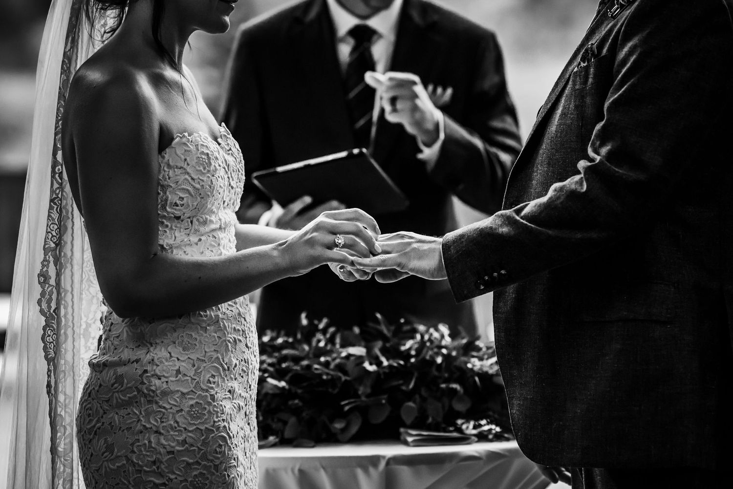 Close-up black and white shot of a ring exchange during a wedding ceremony.