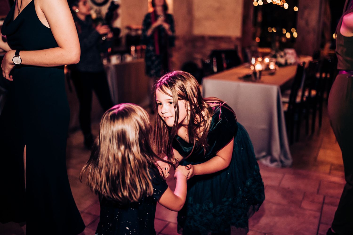 Joyful dancing and interaction between guests at a dimly lit reception venue.