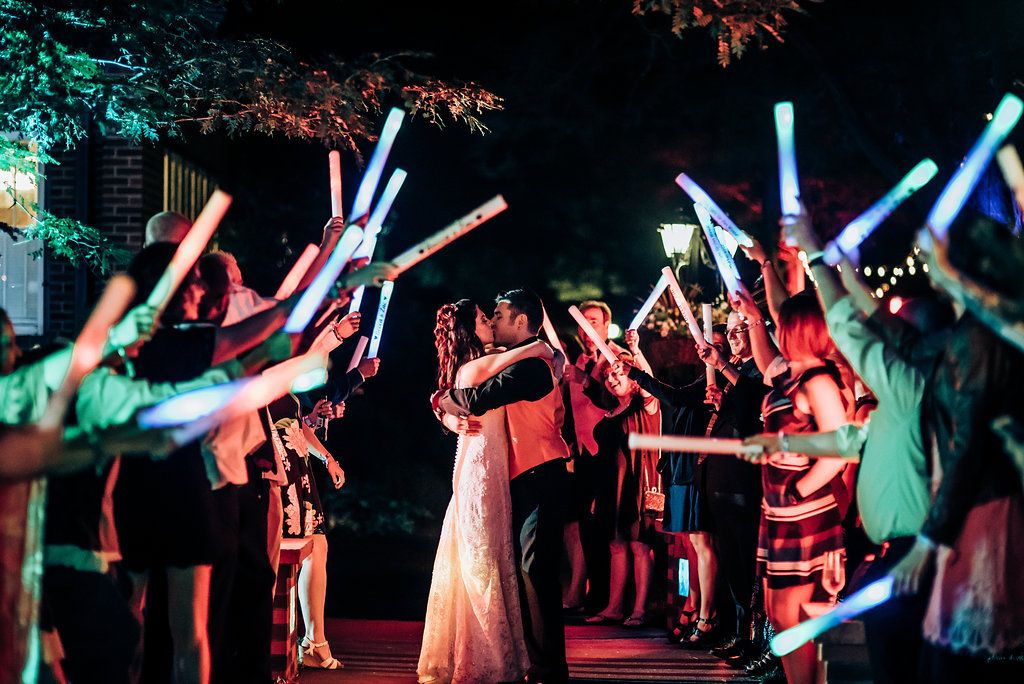 Celebratory nighttime scene with crowd holding glowing LED wands in various colors.
