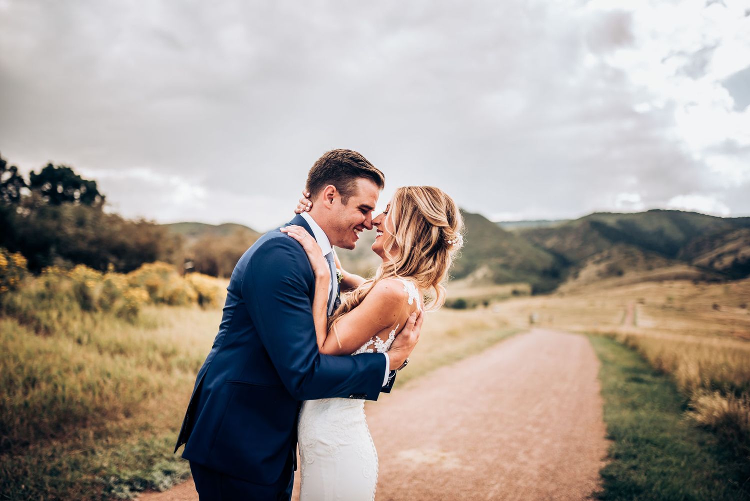 Romantic moment captured between couple on mountainside dirt path during sunset.