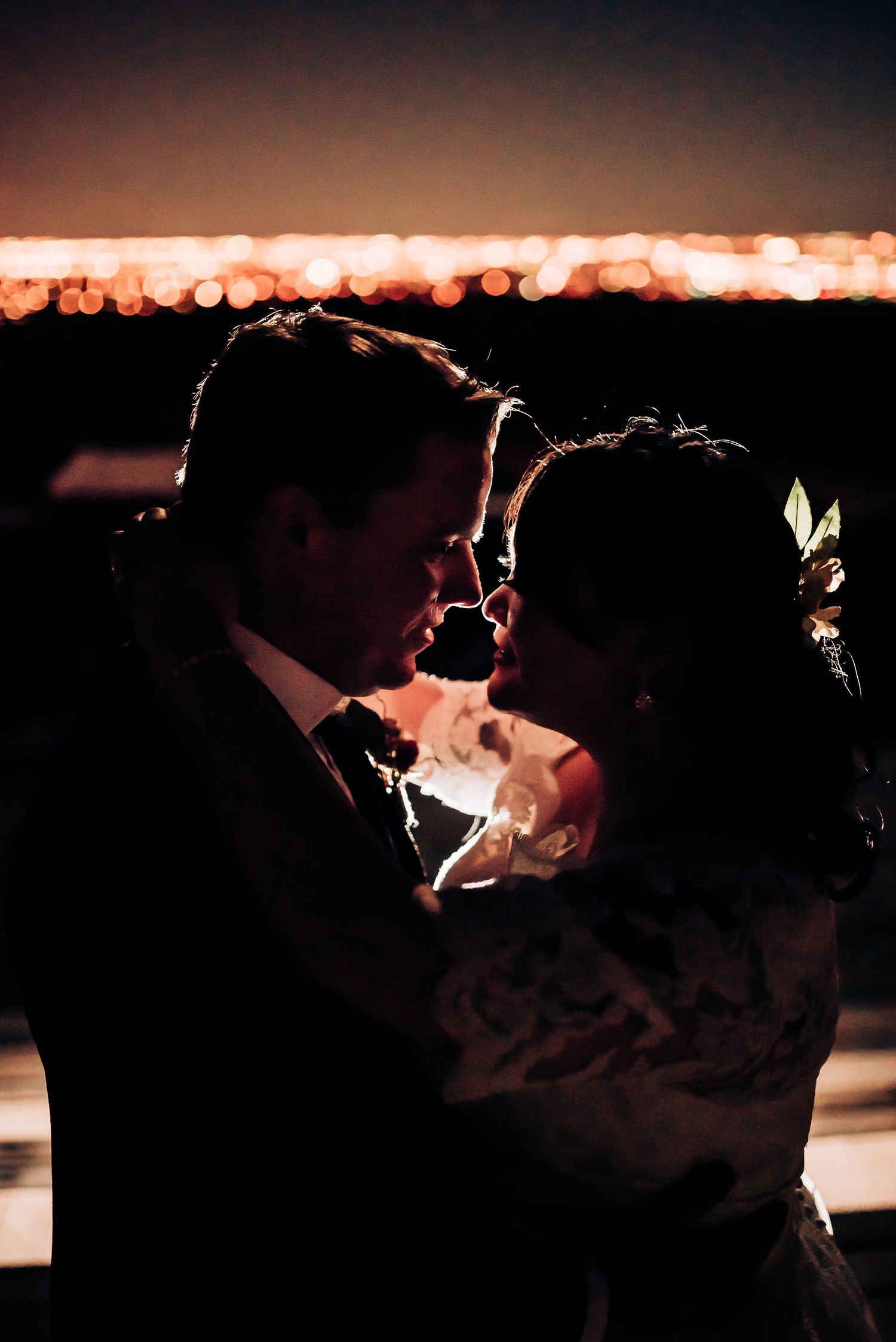 Romantic silhouette of couple illuminated by bokeh lights at sunset.