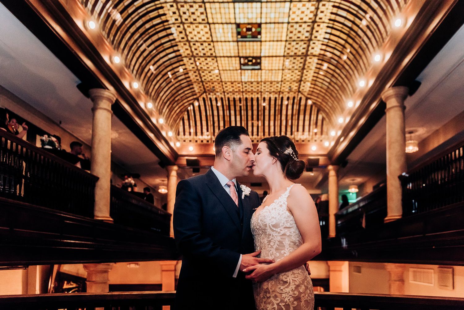 Romantic moment in an elegant venue with arched ceiling and dramatic lighting.