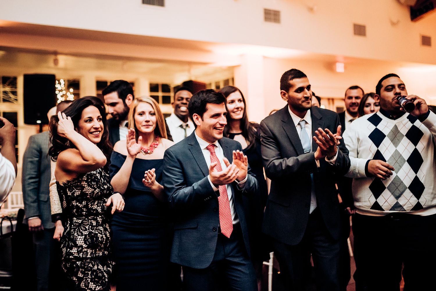 Wedding guests clapping and cheering during a festive reception celebration.