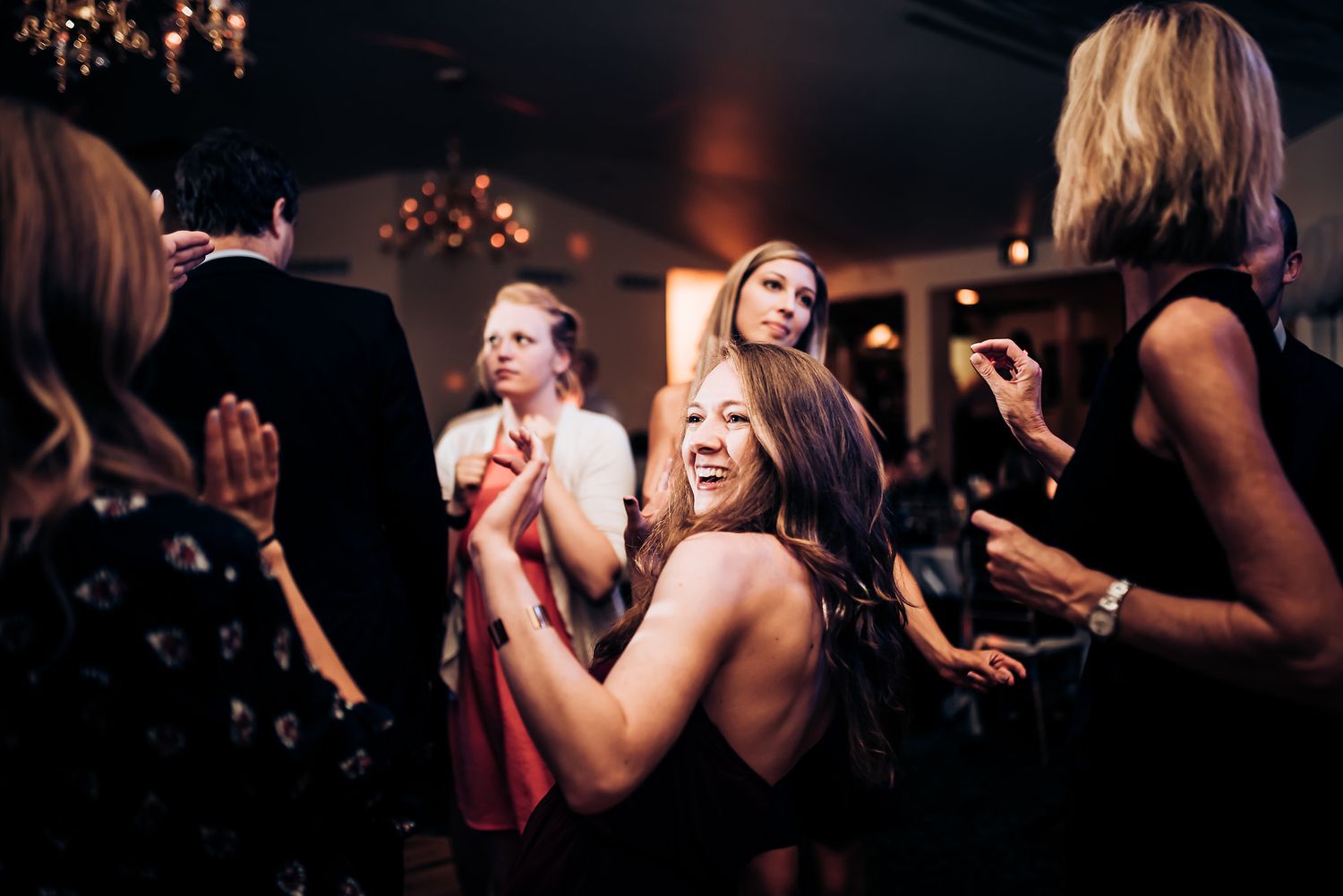 Energetic party guests dancing and laughing together at an evening celebration.