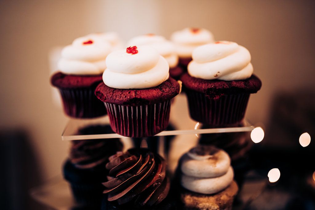 Red velvet and chocolate cupcakes with white frosting arranged on a dessert display.
