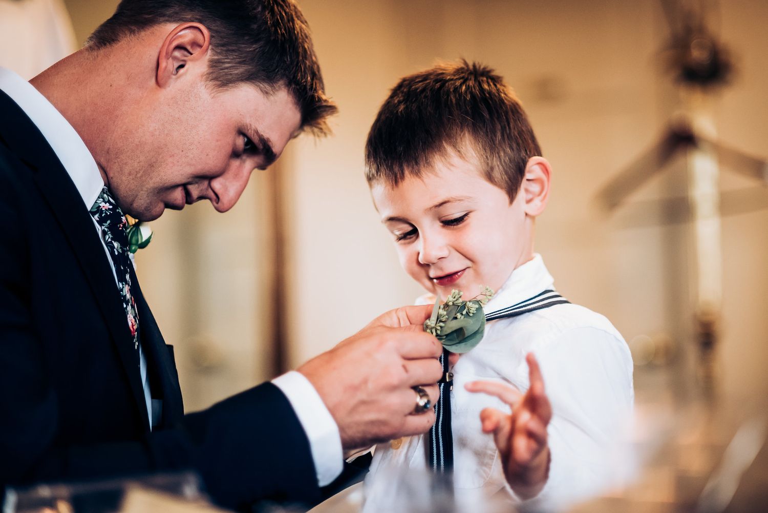 Sweet moment of attaching boutonniere during wedding preparations.