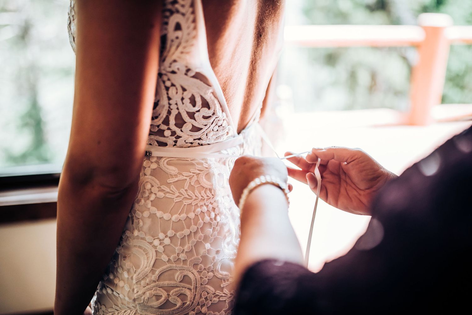 Close up detail shot of intricate lace on a wedding dress being fastened.