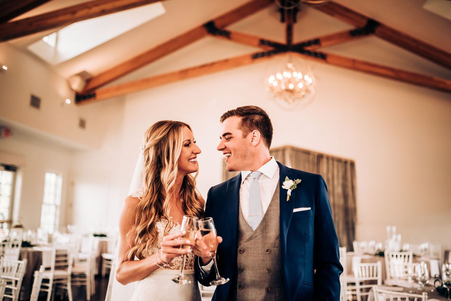 Couple shares intimate moment together in elegant indoor reception venue with wooden beams.