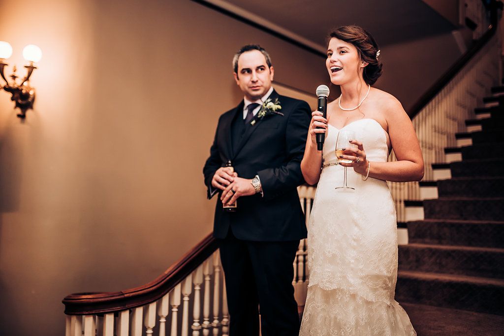 Candid moment during wedding speeches on an elegant staircase.