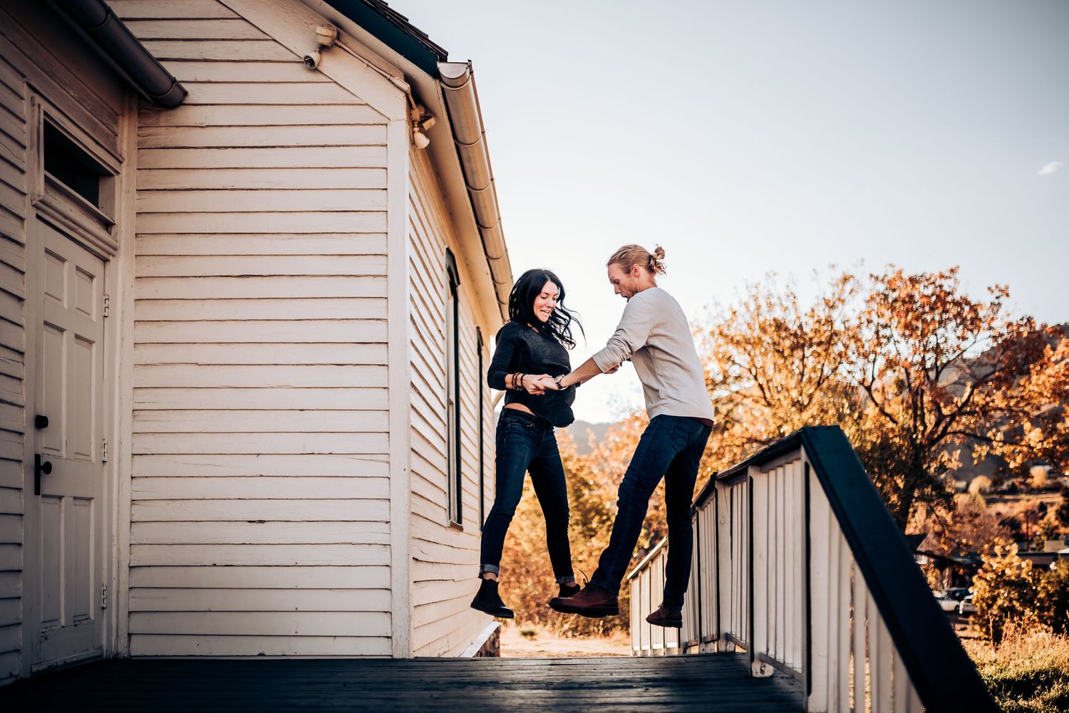 A couple dances and balances on porch railings in autumn.