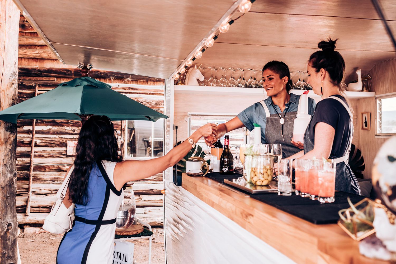 Bar service counter at an outdoor venue with staff serving customers.