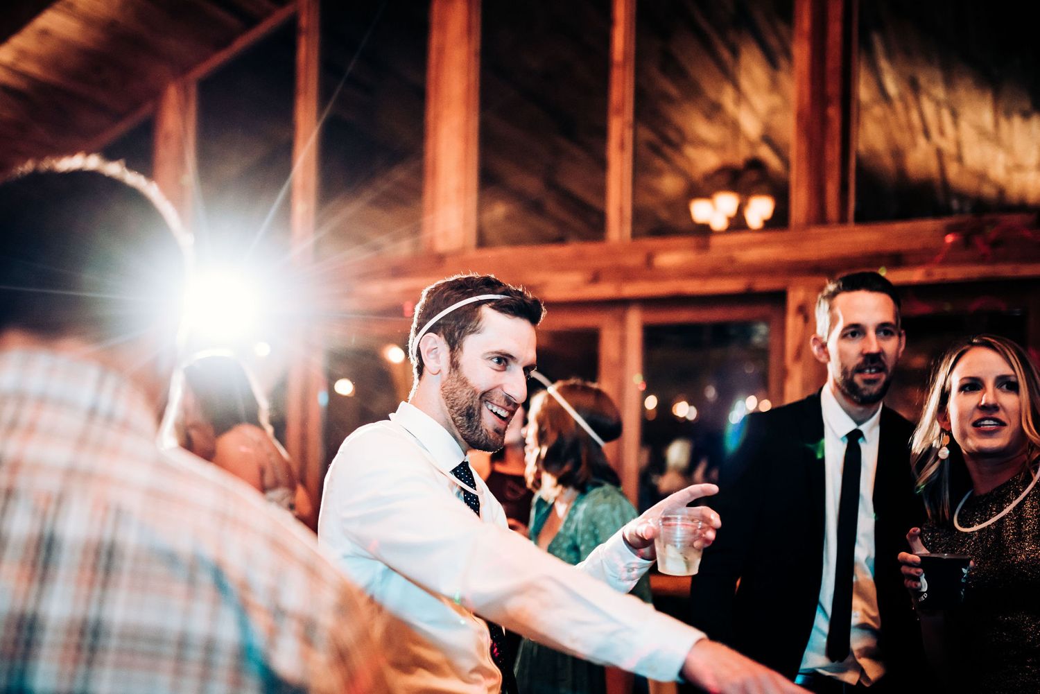 Energetic party scene at indoor wedding reception with bright camera flash.