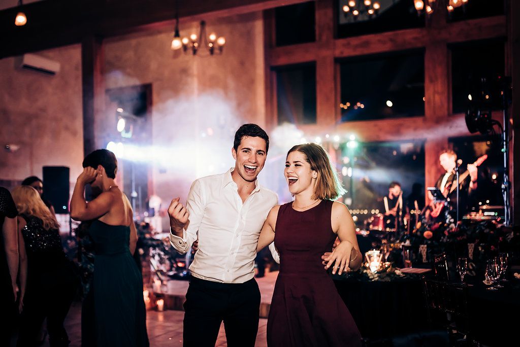 Couples dancing and enjoying themselves at indoor celebration with mood lighting.