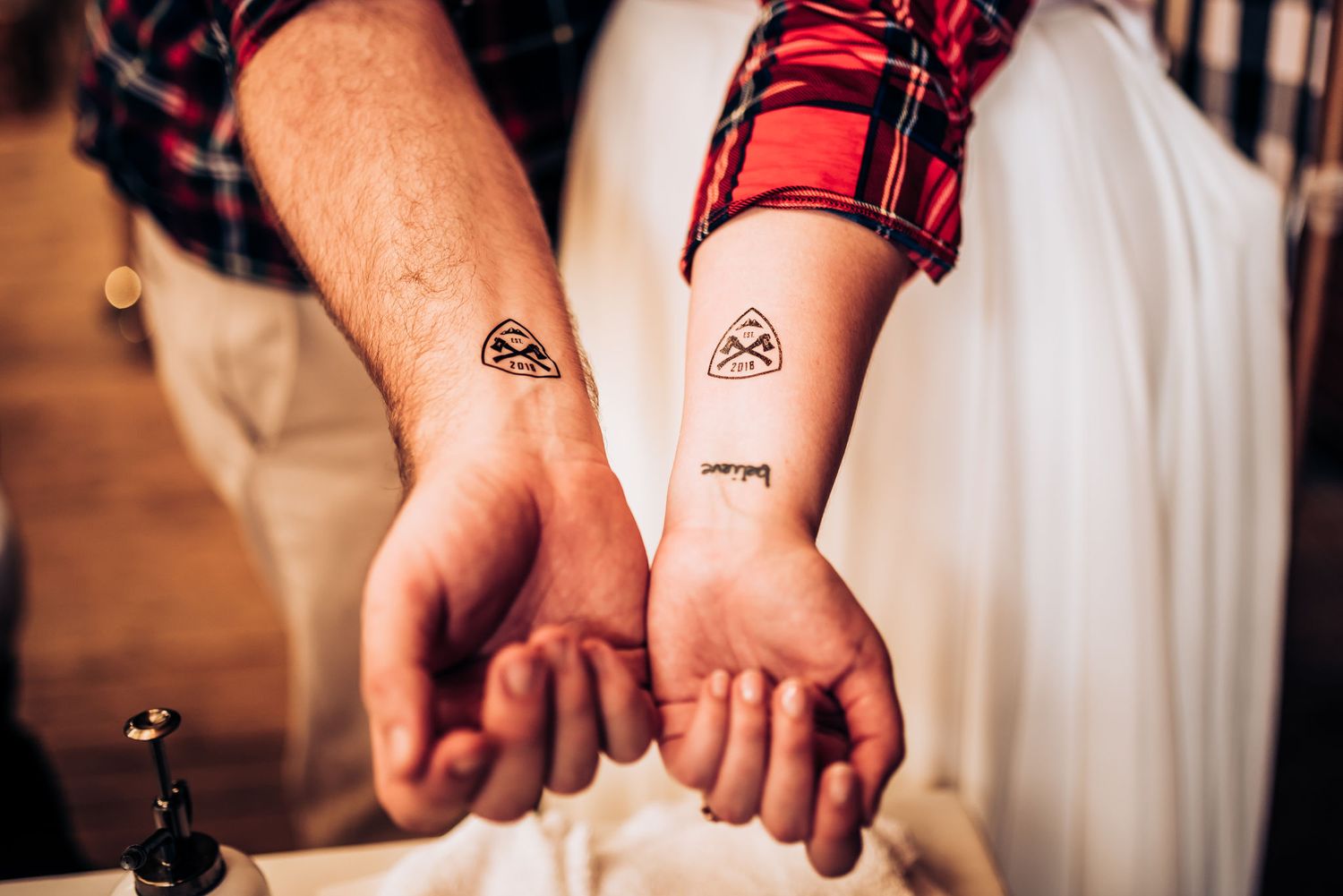Close up of matching tattoos on two wrists at a wedding celebration.