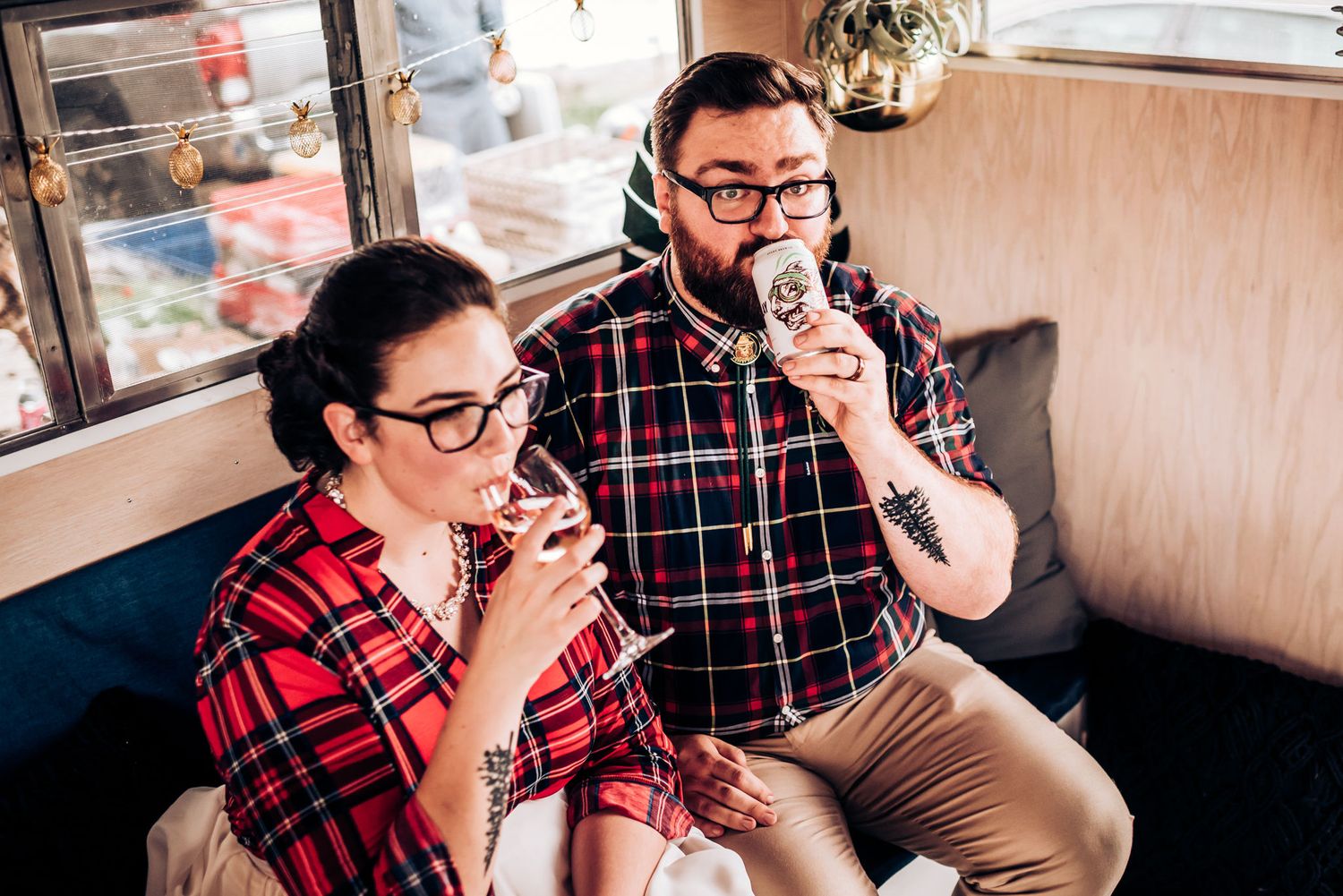 A couple in matching plaid shirts sharing drinks in a cozy diner booth.