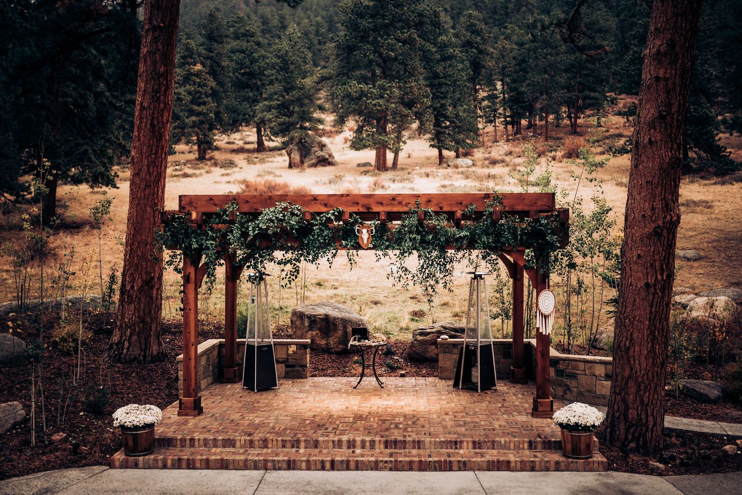 Rustic wooden wedding arch decorated with greenery in a forest setting.