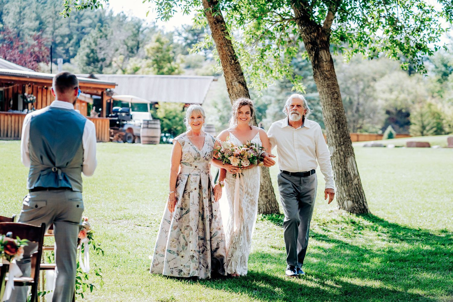 Wedding ceremony processional walking through sunlit outdoor venue.