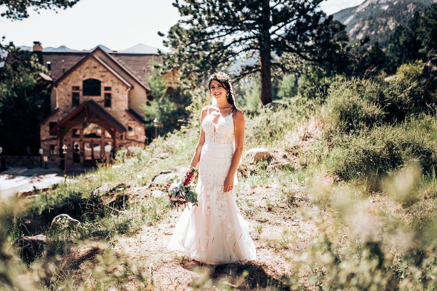 Lace wedding dress photographed against rustic mountain backdrop with stone building.