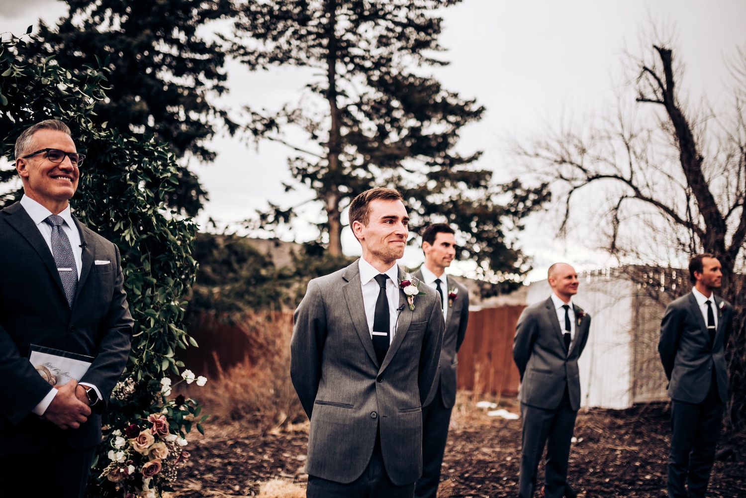 Outdoor wedding ceremony in progress with guests seated on white chairs.