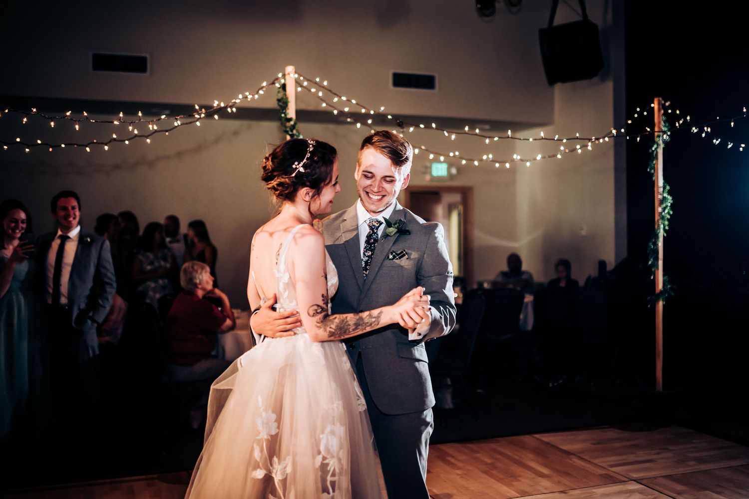 A couple shares their first dance under twinkling fairy lights at their wedding reception.