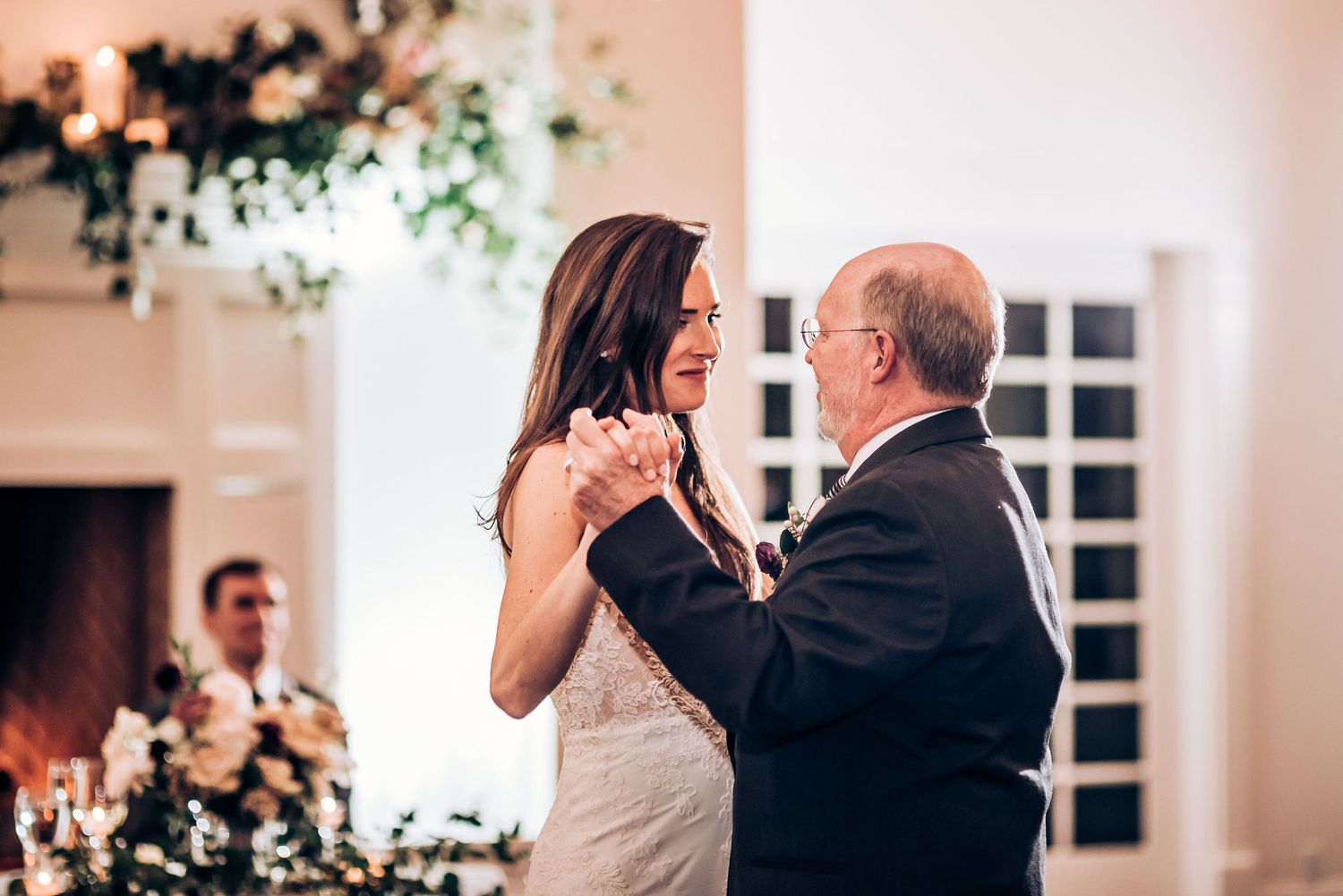 A heartwarming dance moment at an indoor wedding reception with floral decorations.