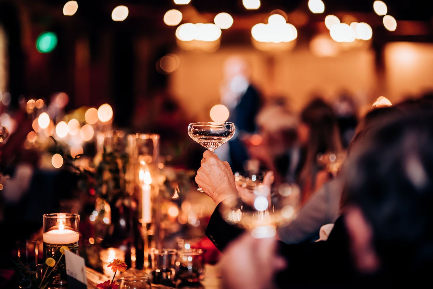 Close-up of wine glasses and candles on elegantly set dinner tables.