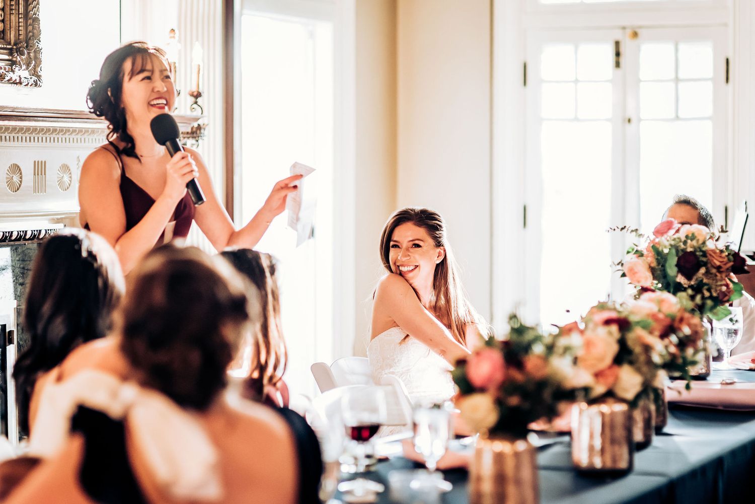 Emotional toast being given during formal dinner with floral centerpieces and wine glasses.