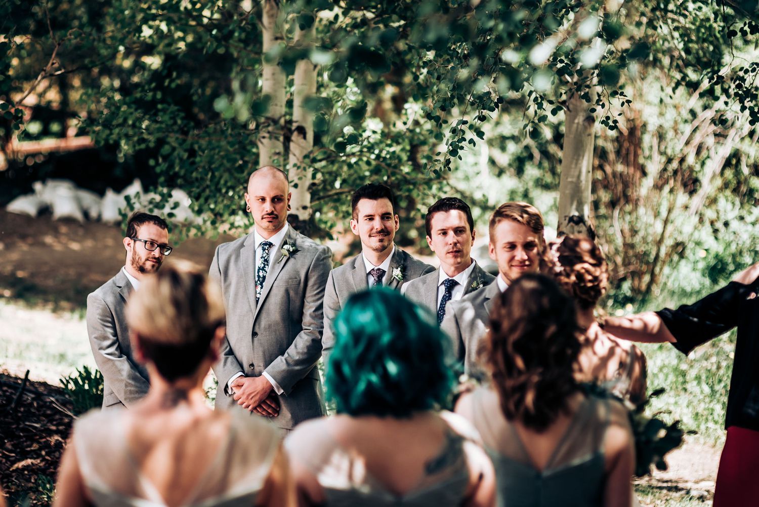 Wedding party standing in formation during an outdoor ceremony among aspen trees.
