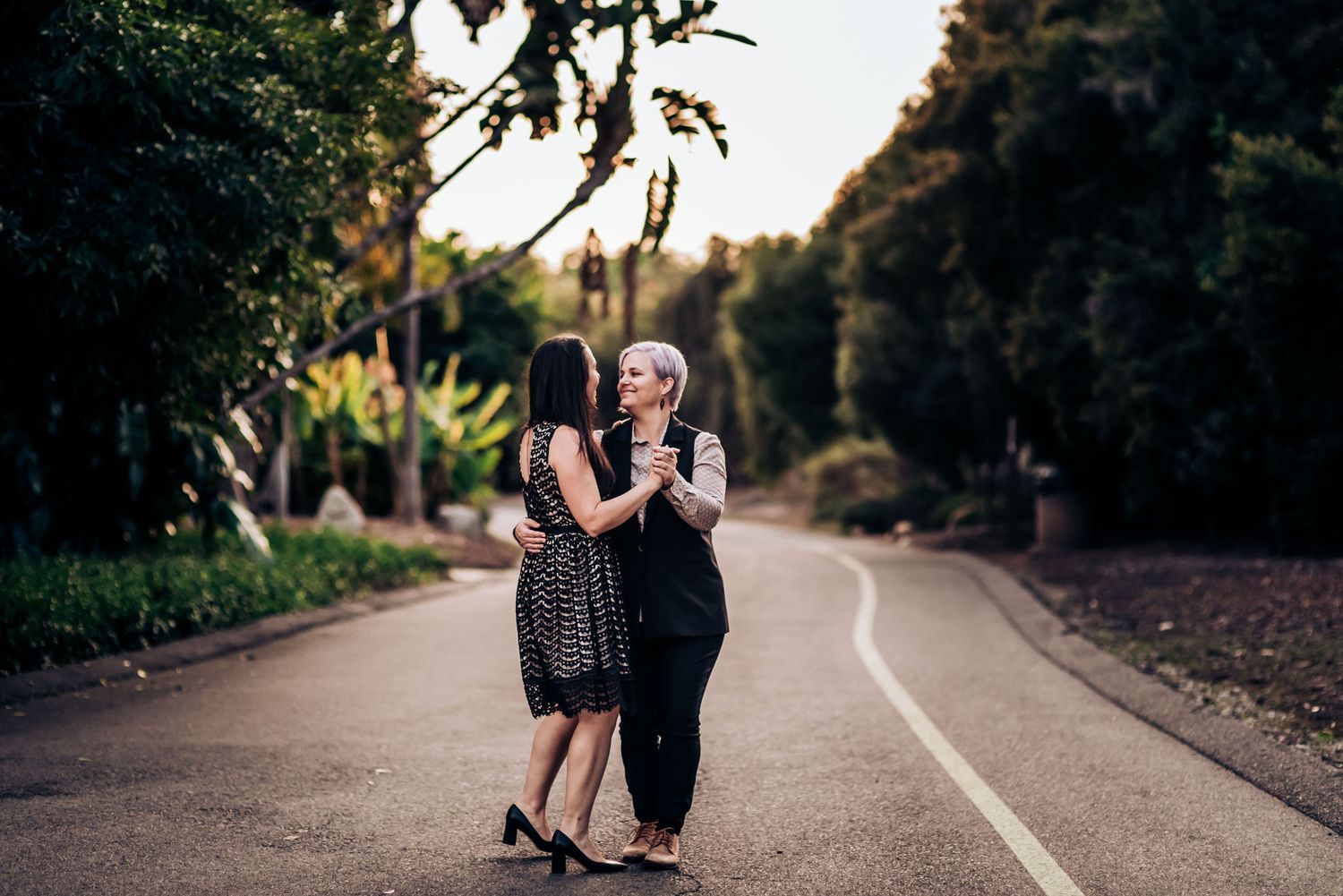 Two people sharing a dance moment on a curved garden pathway at dusk.