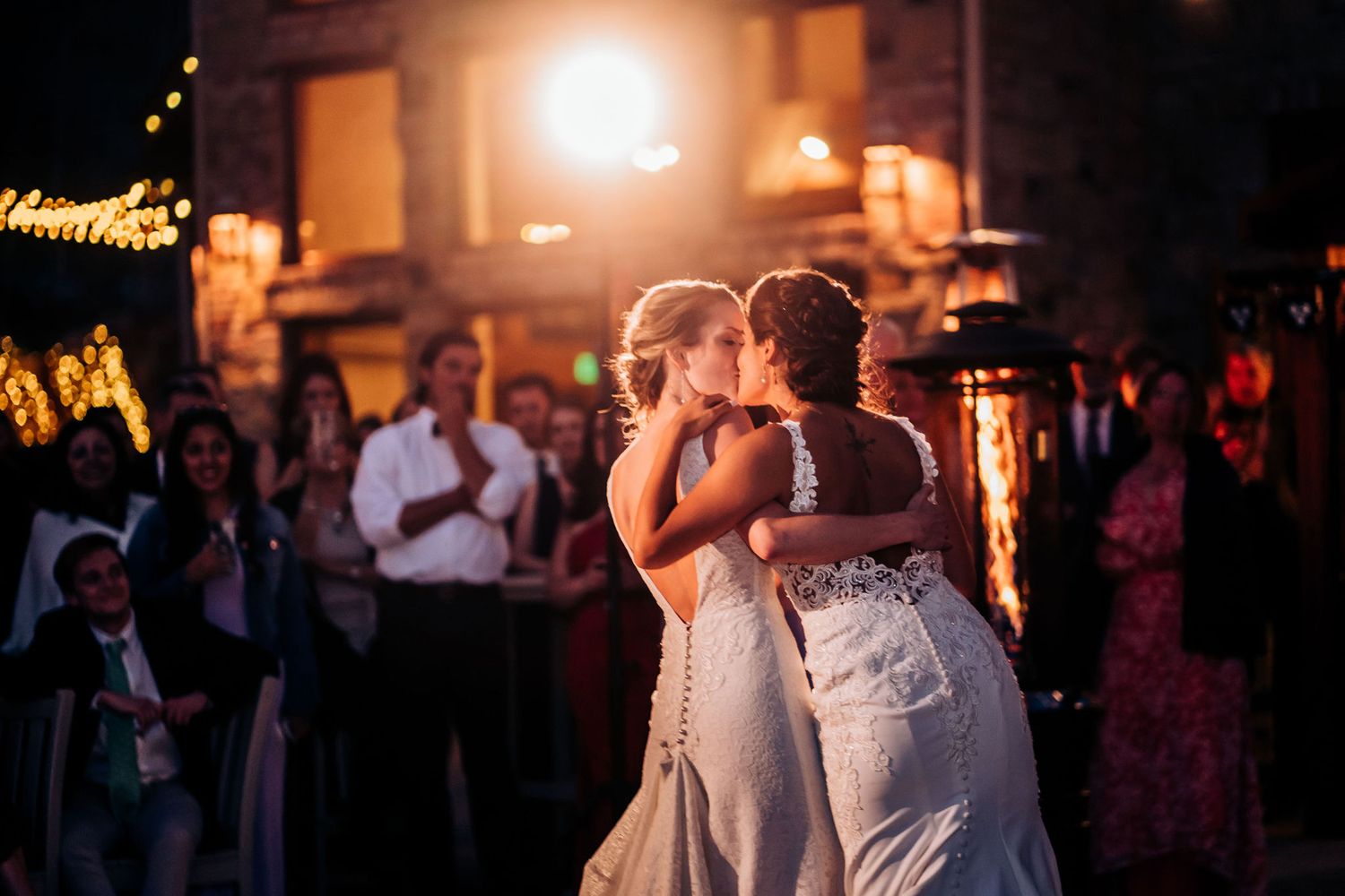 A romantic slow dance moment at an outdoor evening wedding reception.
