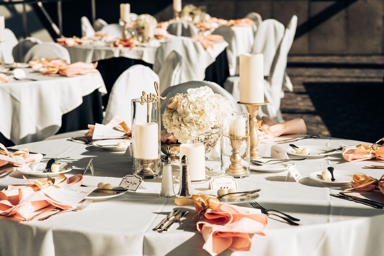 Elegant wedding reception table setting with white linens, floral centerpieces and glowing candles.