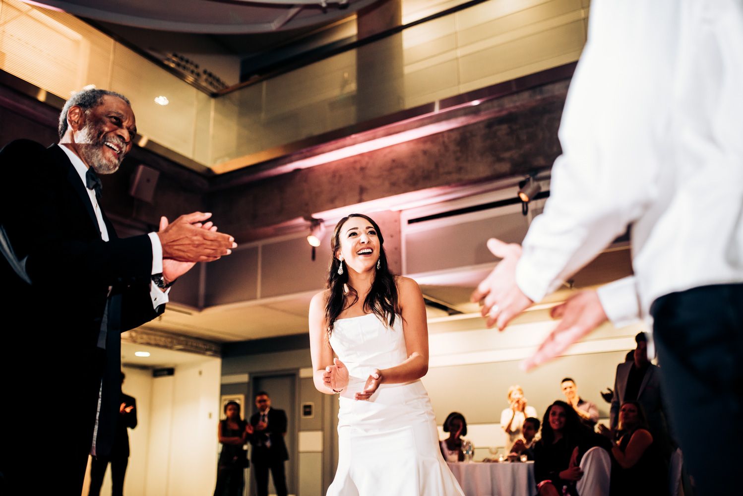 A couple dances at their wedding reception while guests watch from the side.