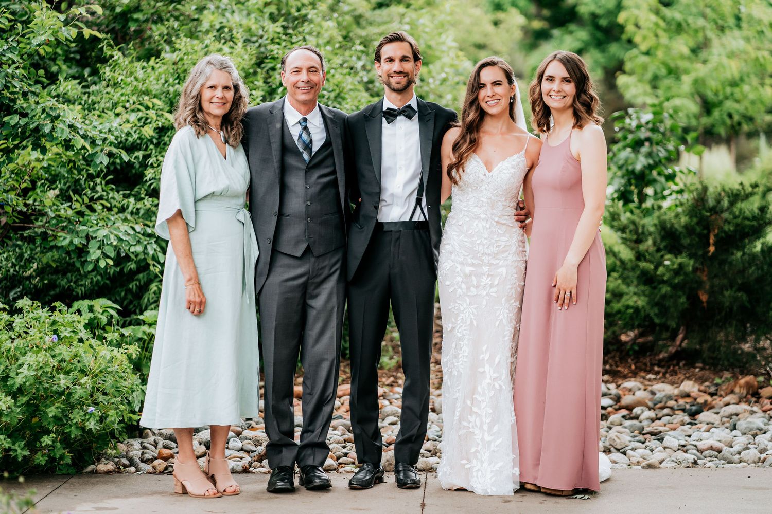 Wedding party poses together outdoors in coordinated formal attire.