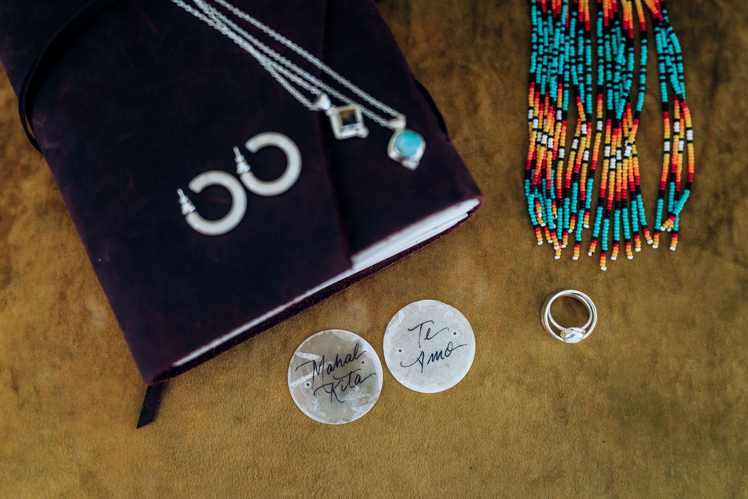 Wedding rings and turquoise beaded jewelry displayed next to a black cloth.
