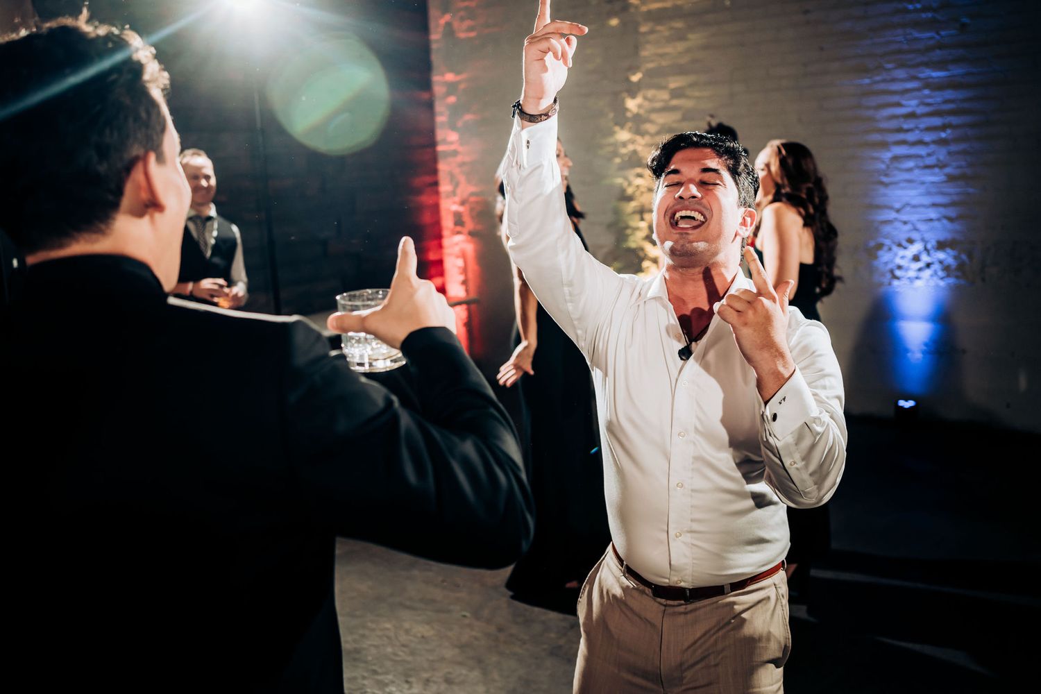 Wedding guest dances enthusiastically during reception party with hands raised in celebration.