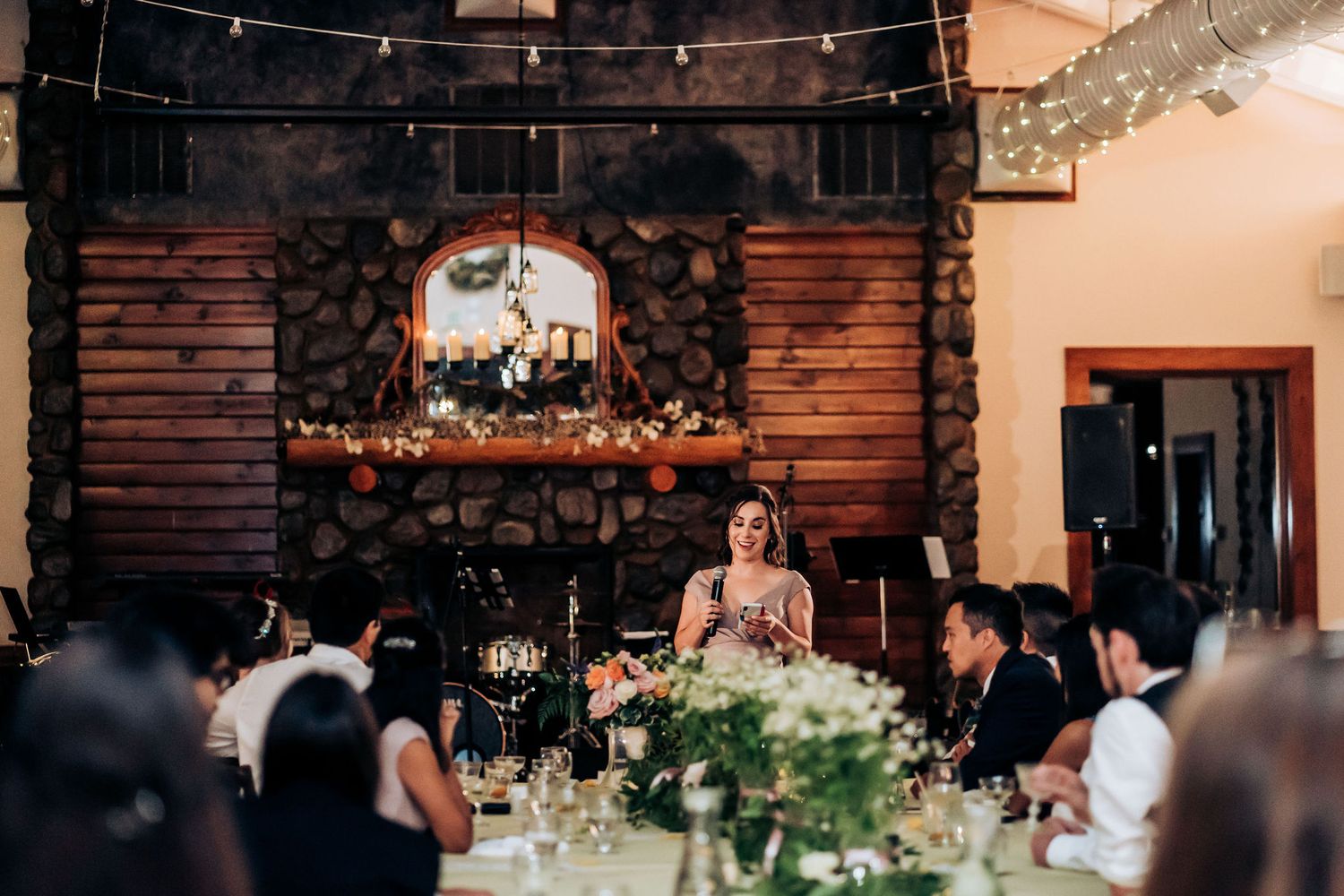 Elegant wedding reception venue with rustic wooden fireplace and floral decorations.