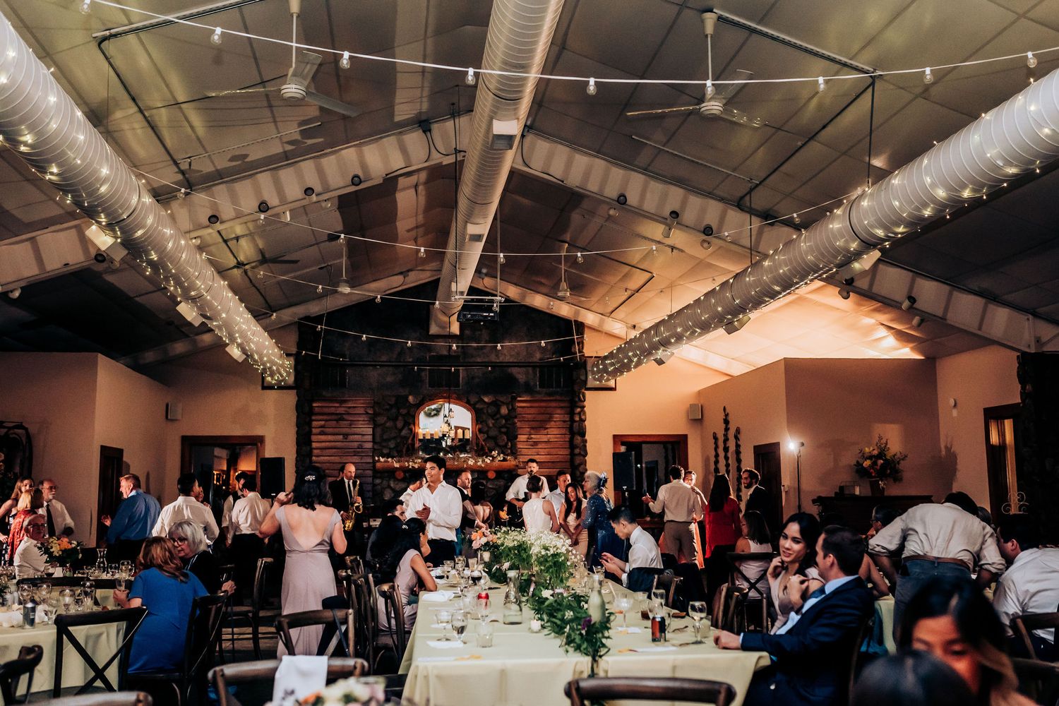 Reception venue decorated with string lights and greenery features tables set for a celebration.
