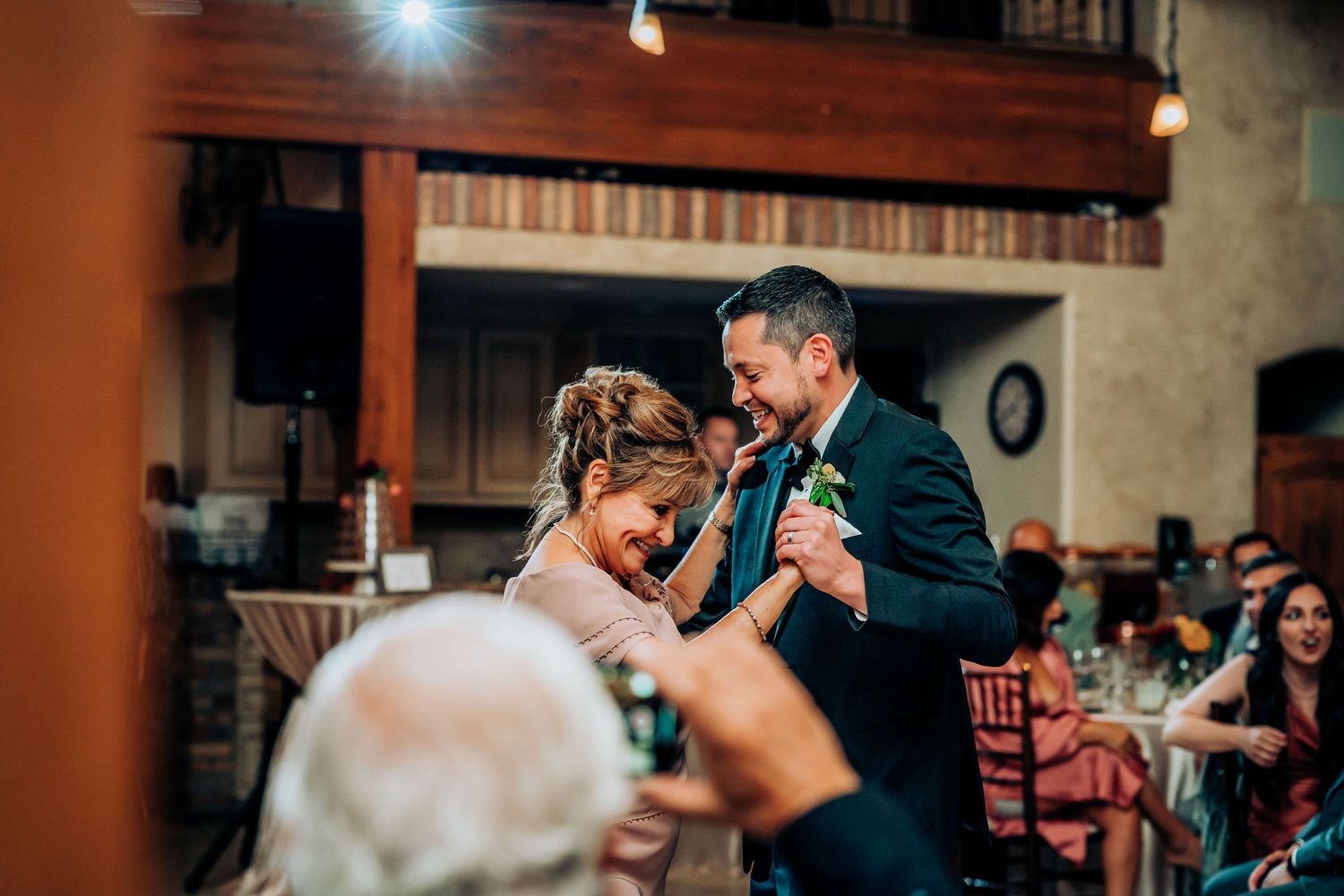 A romantic slow dance moment captured during a wedding reception in a cozy indoor venue.