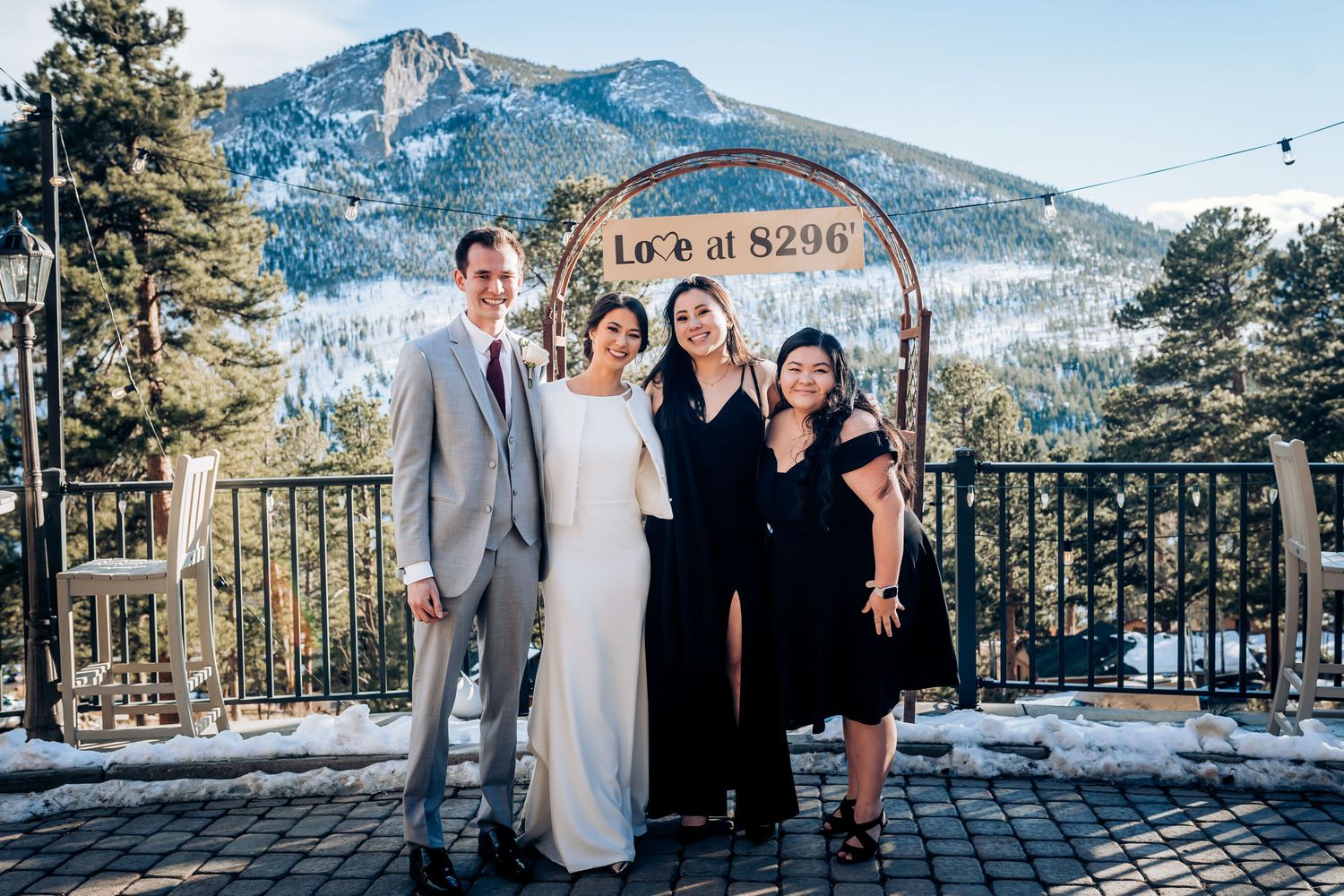 Small wedding group poses against mountain backdrop with Lake Alpine sign visible.