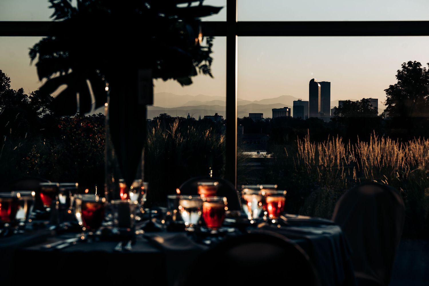 Silhouette of reception tables and city skyline at sunset through large windows.