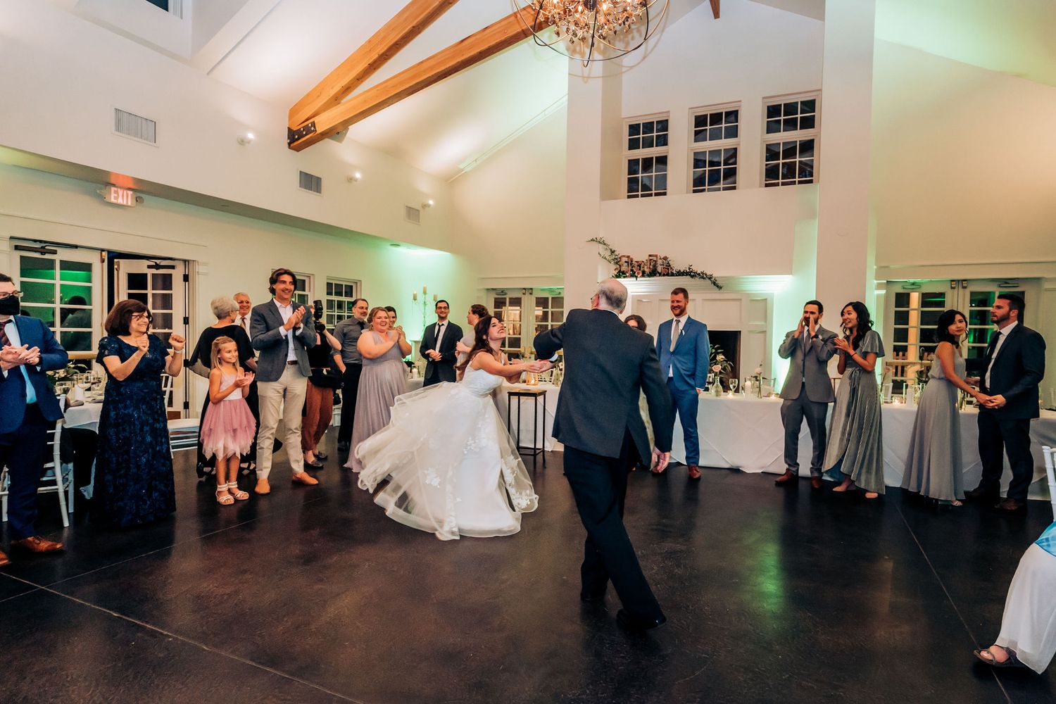 Wedding reception dance floor filled with guests celebrating in elegant venue with wooden beams.
